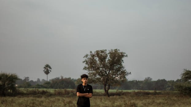 Man standing alone in a tranquil meadow, embodying solitude and introspection.
