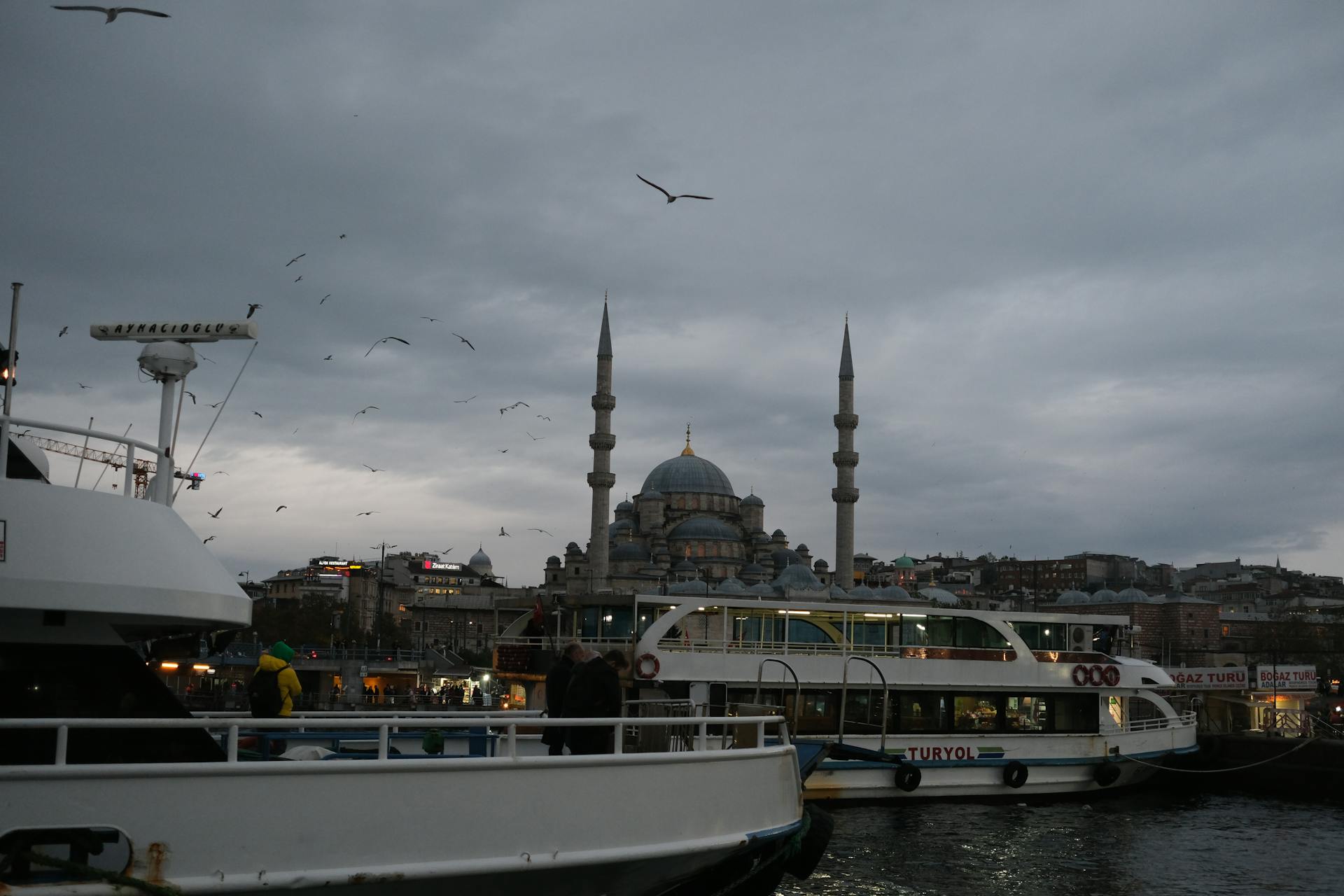 Serene twilight view of Eminönü waterfront with New Mosque and bustling ferries in Istanbul.