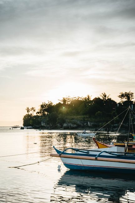 A peaceful boat anchored near a tropical island at sunrise, capturing the essence of summer travel.