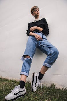 一位穿着破洞牛仔裤和运动鞋的时尚女性在户外斜身拍摄时尚照片