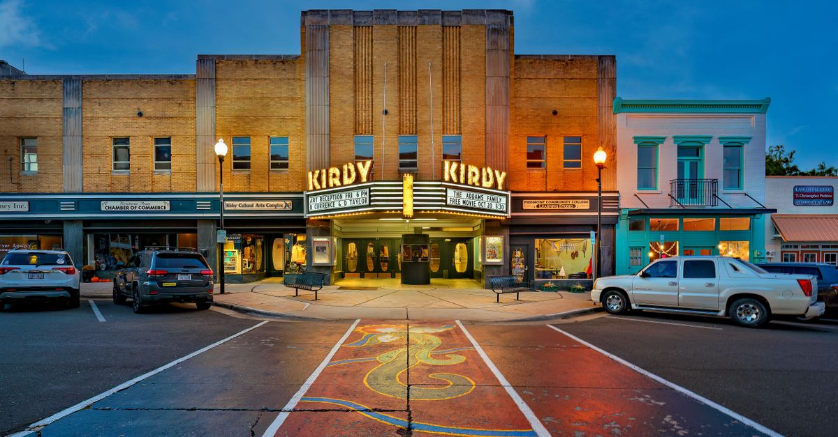 The iconic Kirby Theater glowing at twilight on a bustling street in Roxboro, North Carolina.