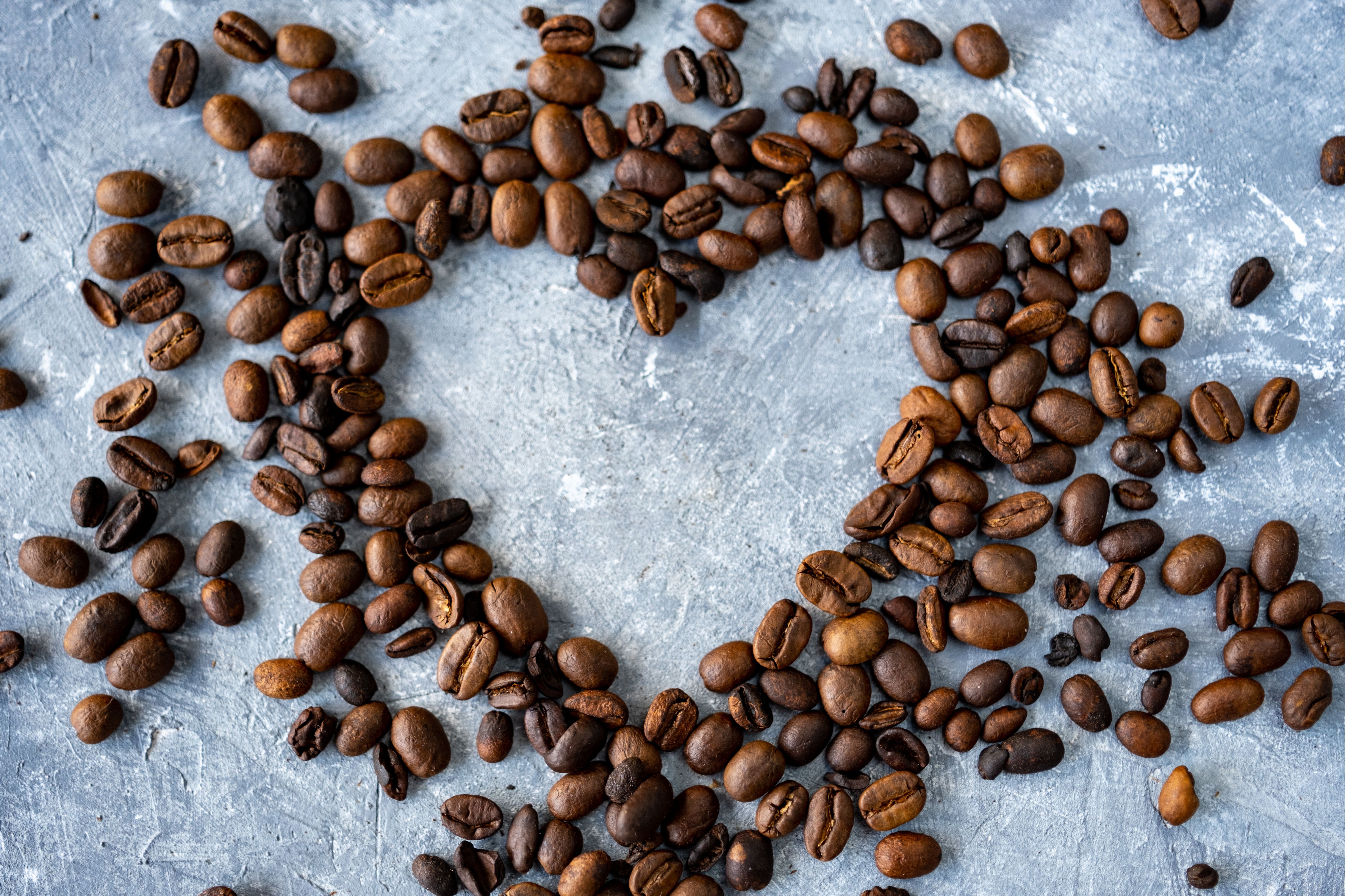 homemade mocha latte recipe - Coffee beans arranged in a heart shape on a textured gray surface.