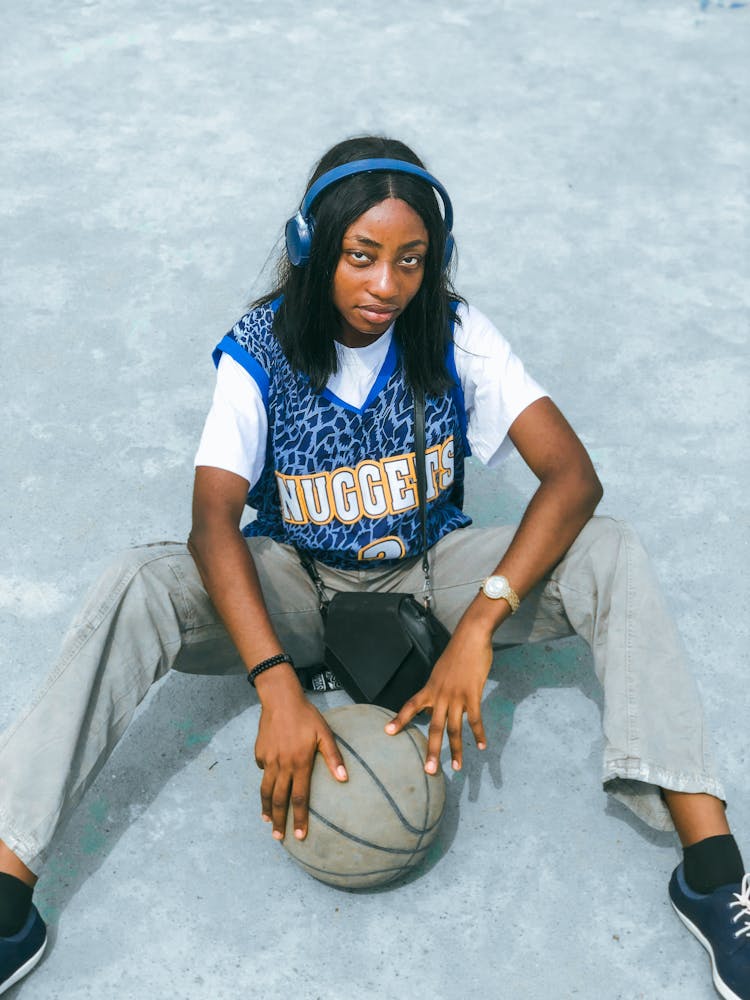 Woman In Wireless Headphones Sitting With A Basketball