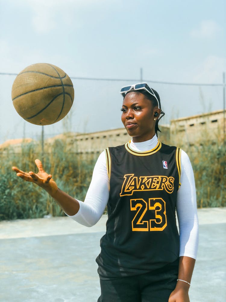 Young Woman In Los Angeles Lakers Jersey Playing With Basketball On Court