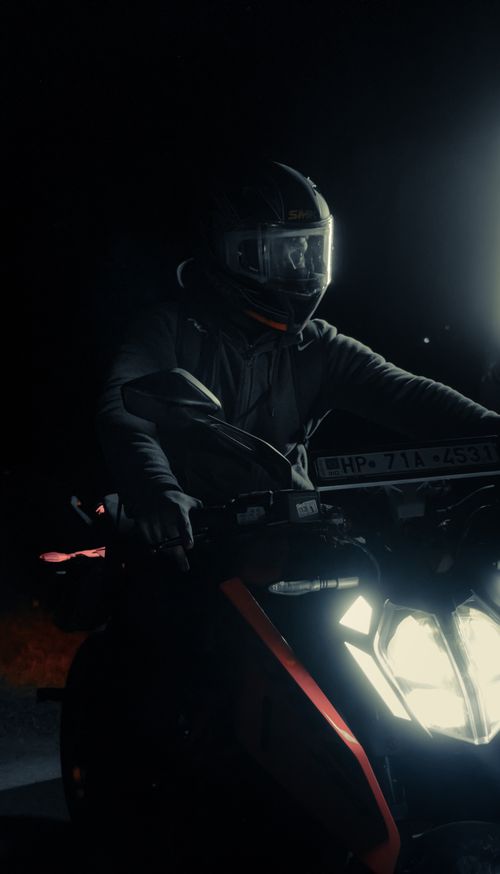 Free A motorcyclist wearing a helmet rides a quad vehicle under bright lights at night in Nahan, HP, India. Stock Photo