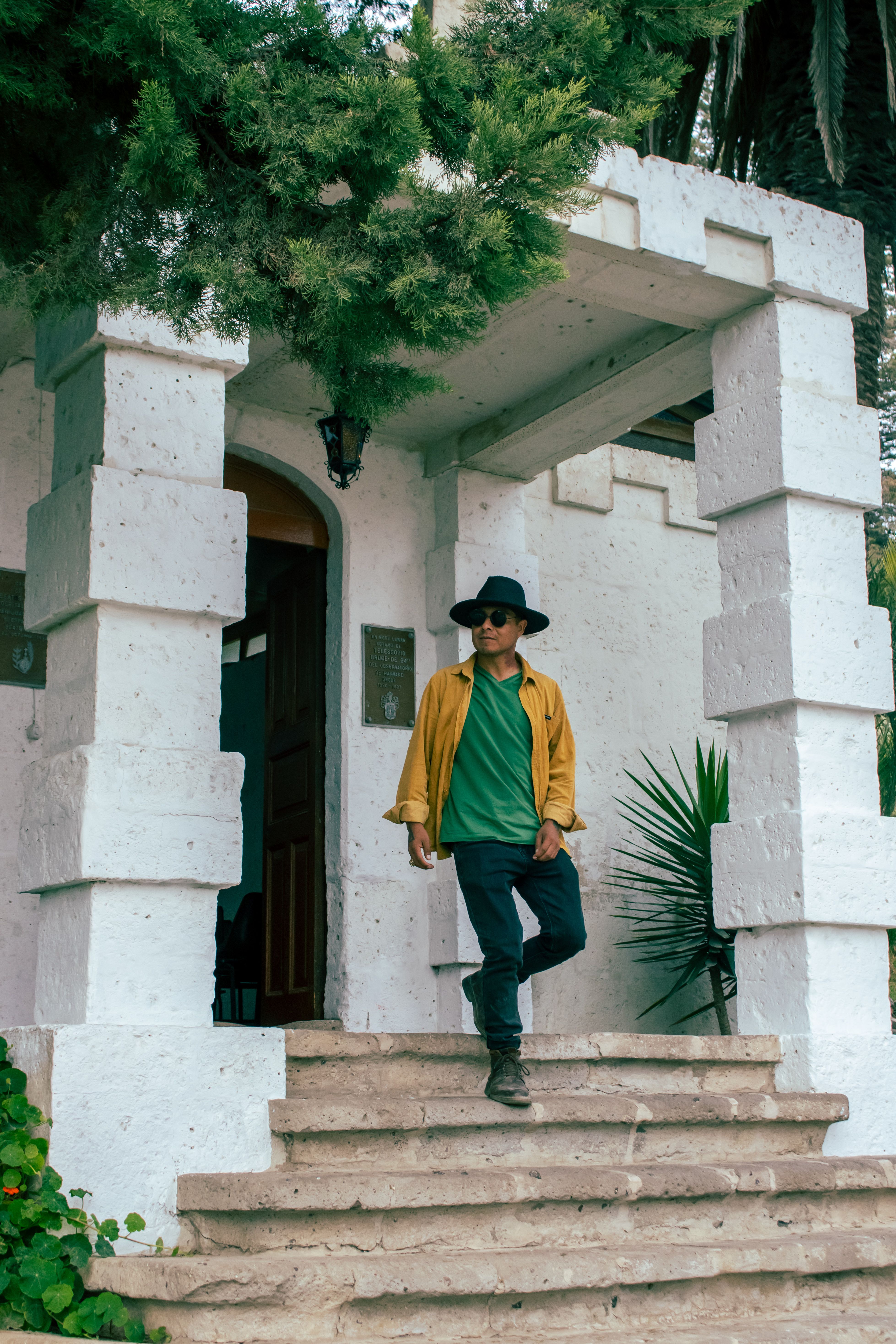 Urban fashion scene with a man in sunglasses and a hat on stone steps.