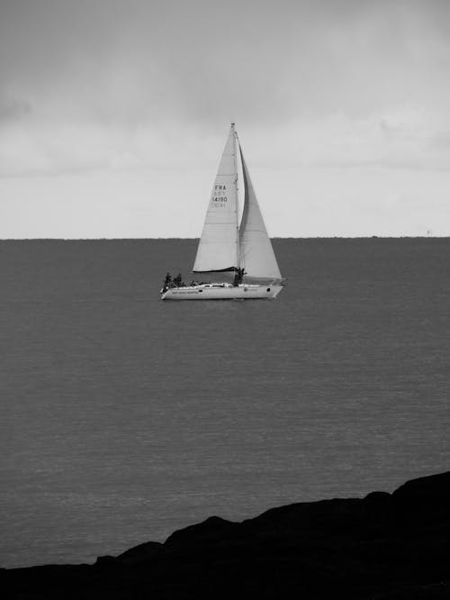 Black and White Shot of a Sailboat at Sea