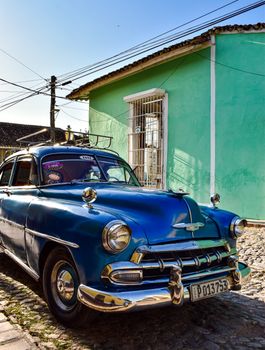 Classic blue Chevrolet car on a sunny, cobblestone street in Cuba.