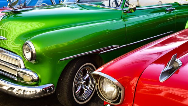 Close-up view of vintage green and red classic Chevrolet cars parked together, showcasing retro style.