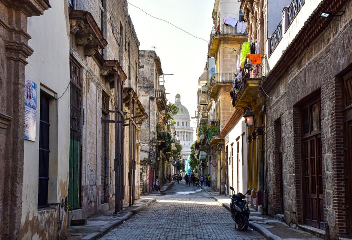 Historic alleyway in Old Havana showcasing urban architecture and the iconic Capitol building.