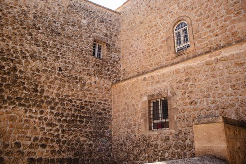 Free Close-up of an ancient stone building exterior in Mardin, Türkiye, featuring barred windows. Stock Photo