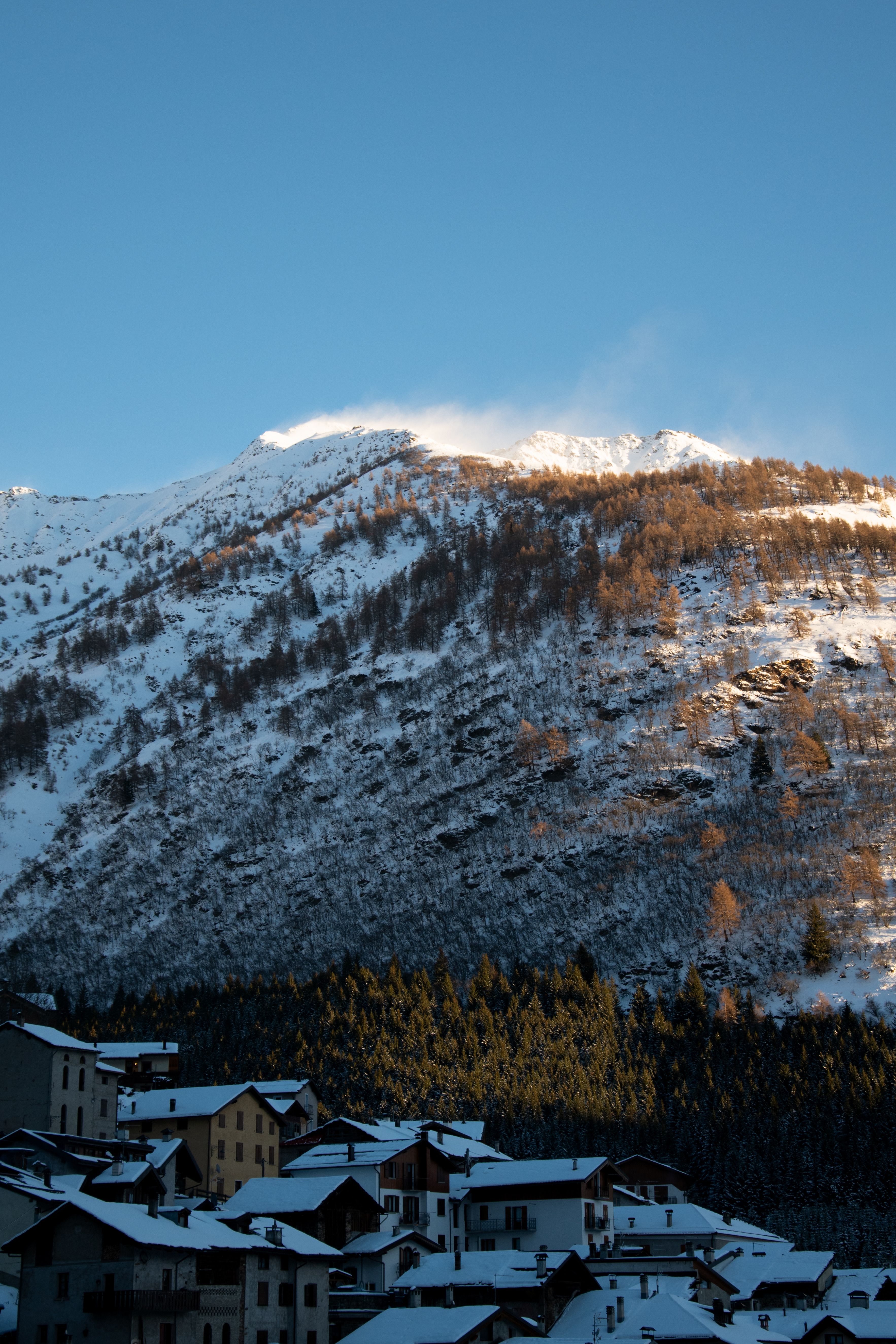 Charming alpine village nestled beneath a snow-covered mountain, capturing the serene essence of winter.