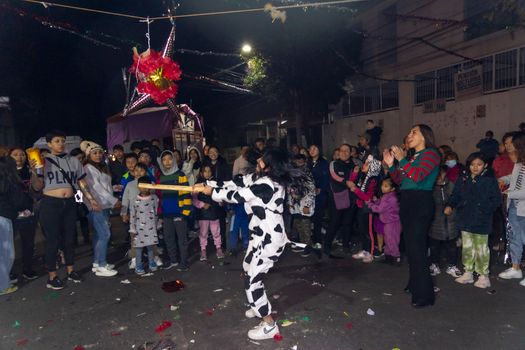 Joyful night piñata party in Coyoacán, México with a lively crowd gathered outdoors.