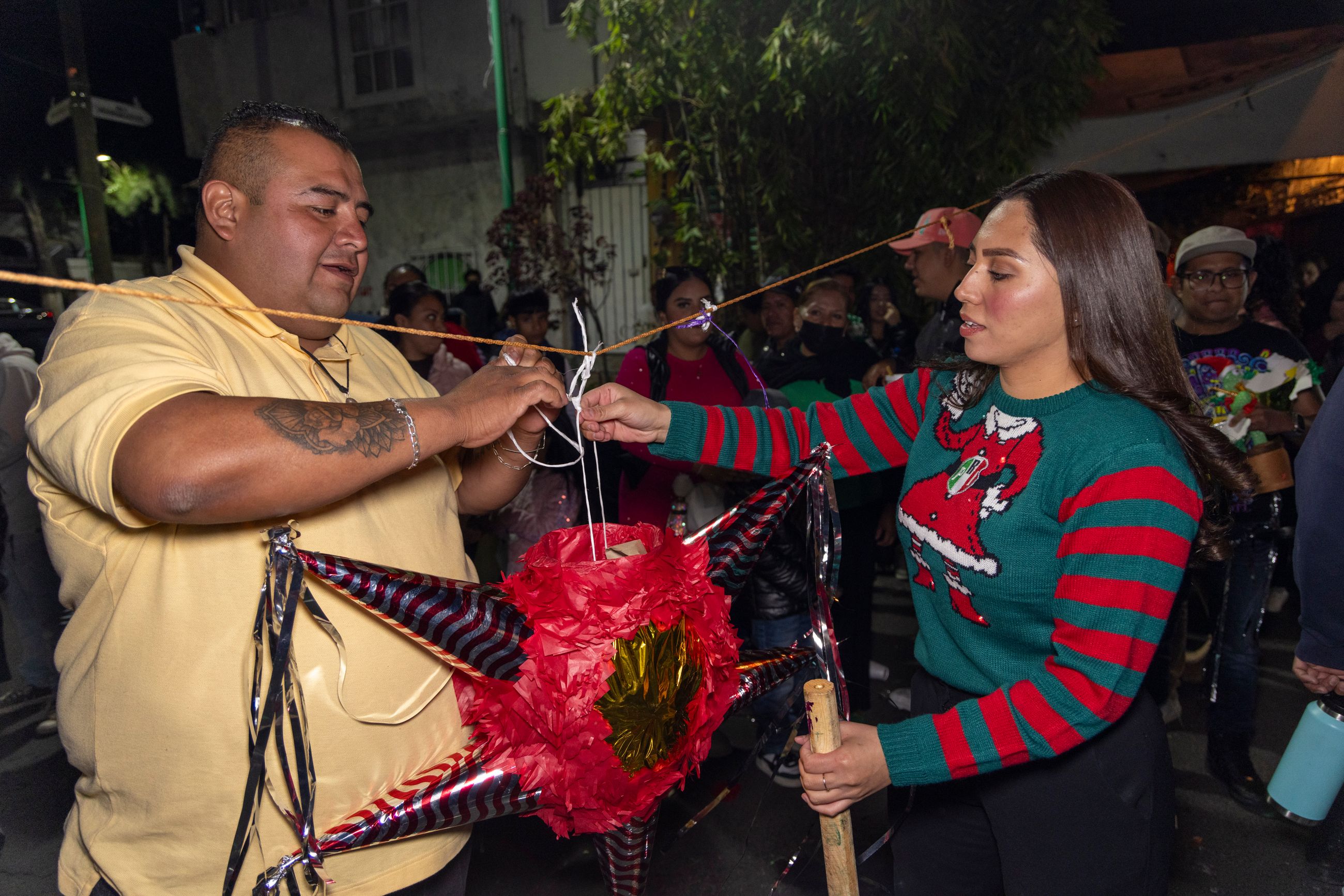 Deux personnes installent une piñata lors d’une fête de quartier au Mexique la nuit