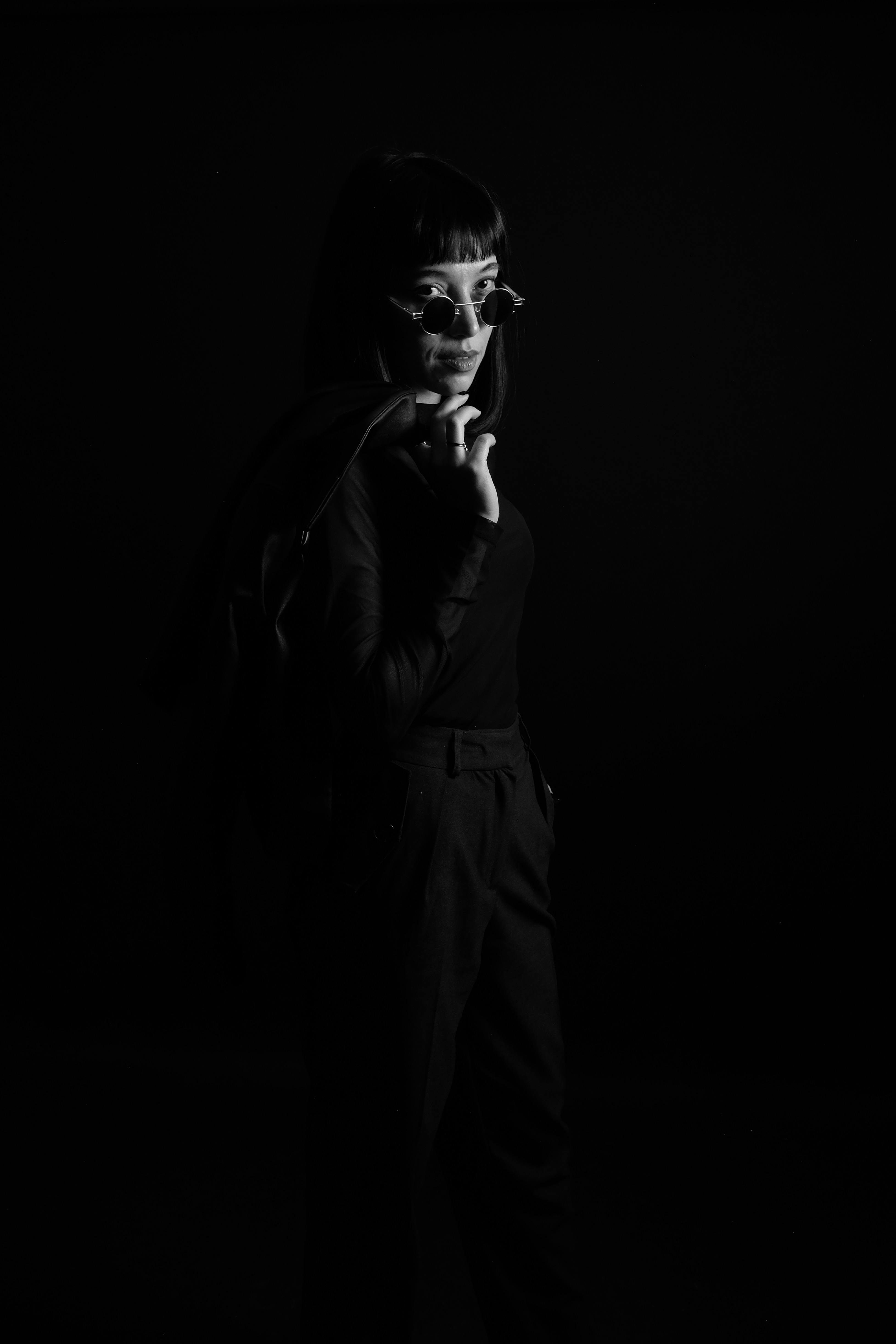 Artistic black and white portrait of a woman in sunglasses with a dramatic pose.