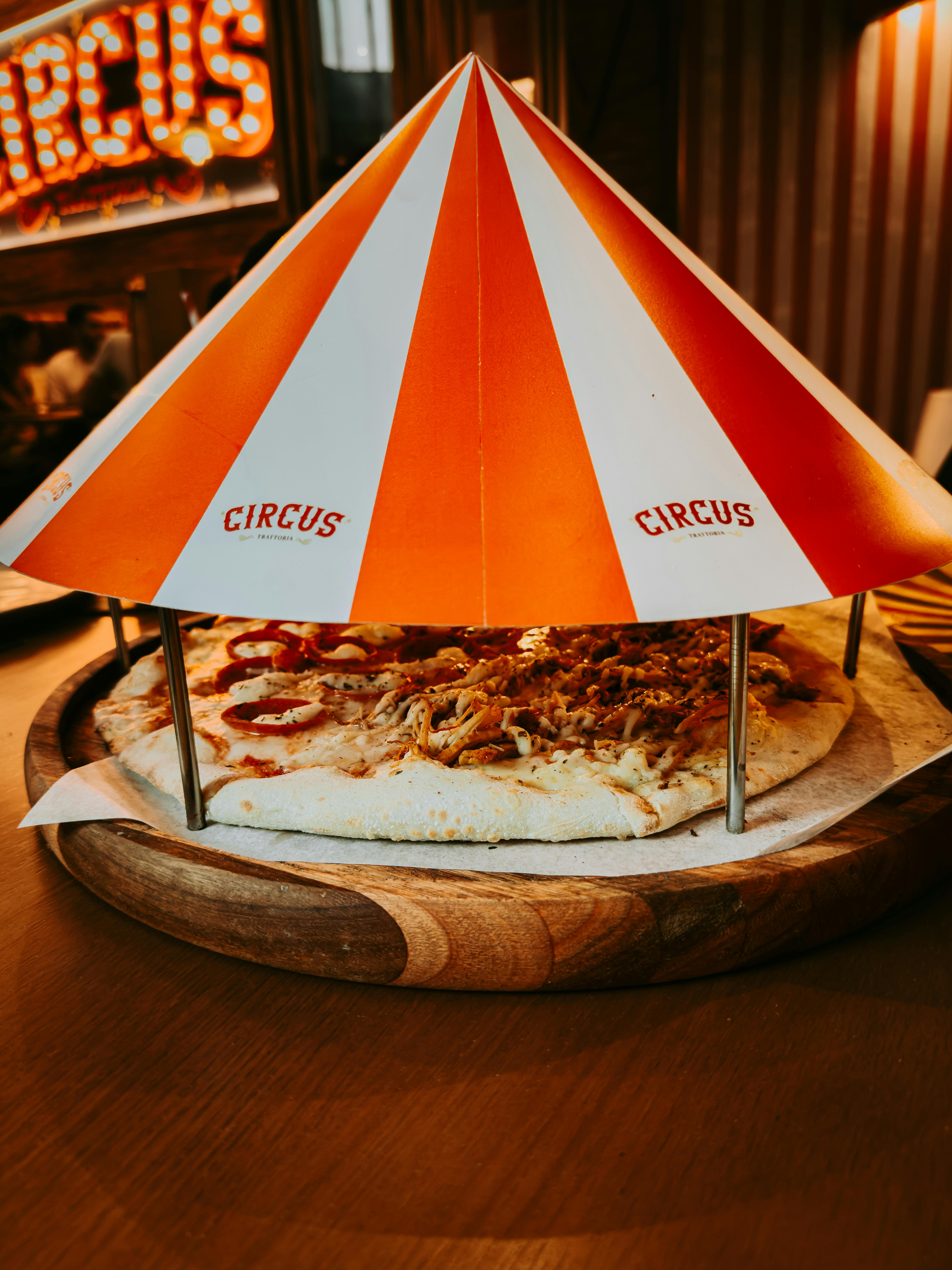 Playful circus-themed pizza presented under a vibrant tent in a Rio de Janeiro eatery.