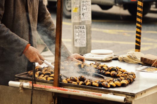 A man roasting chestnuts in a street stall in Istanbul, capturing local culinary tradition.