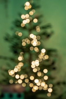 Stylized Christmas tree with warm round bokeh lights on a green background.