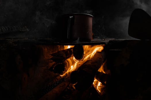 A pot heats on a traditional wood fire stove, capturing rustic cooking vibes.