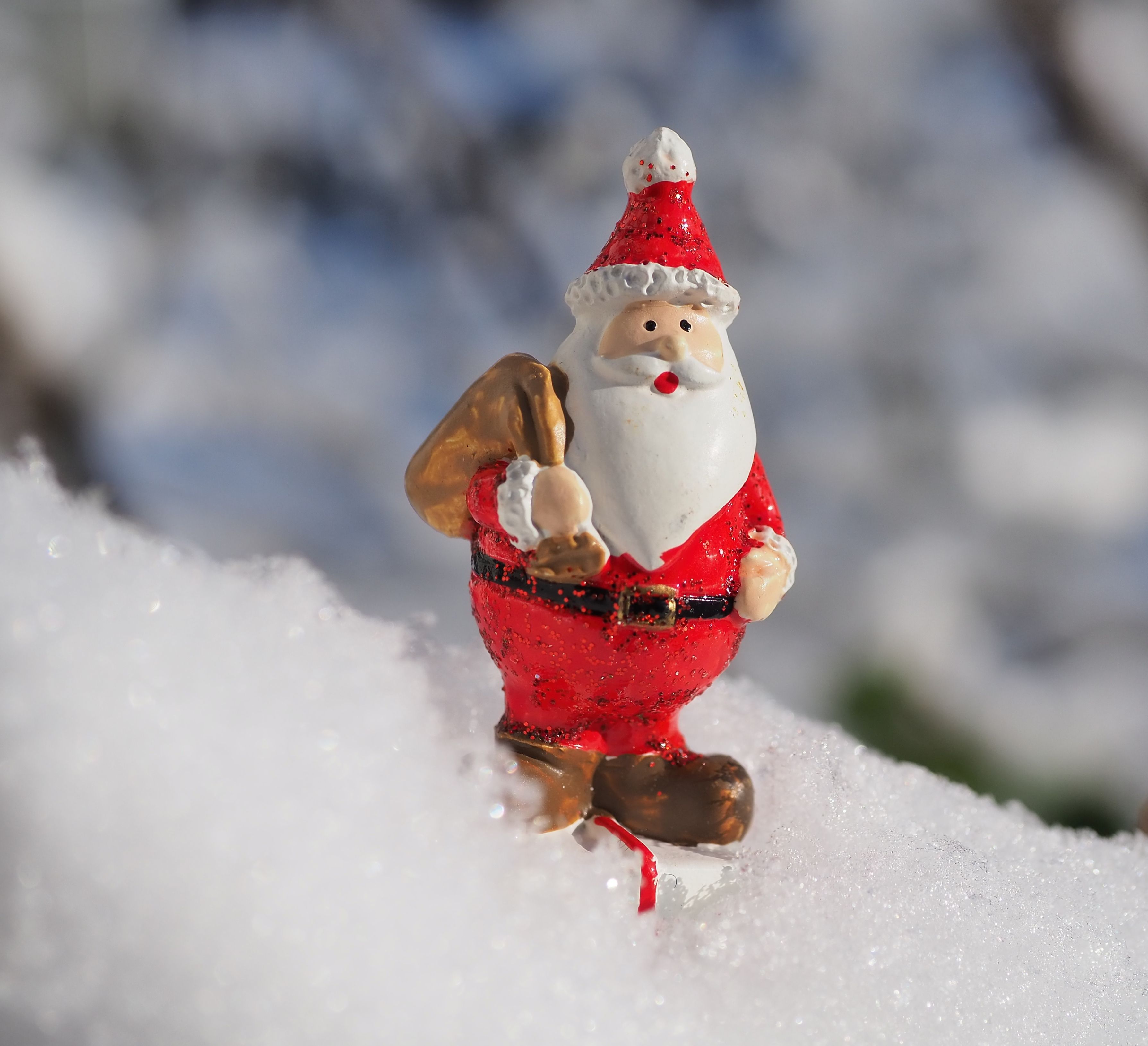 Close-up of a Santa Claus figurine on fresh winter snow, capturing the festive holiday spirit.