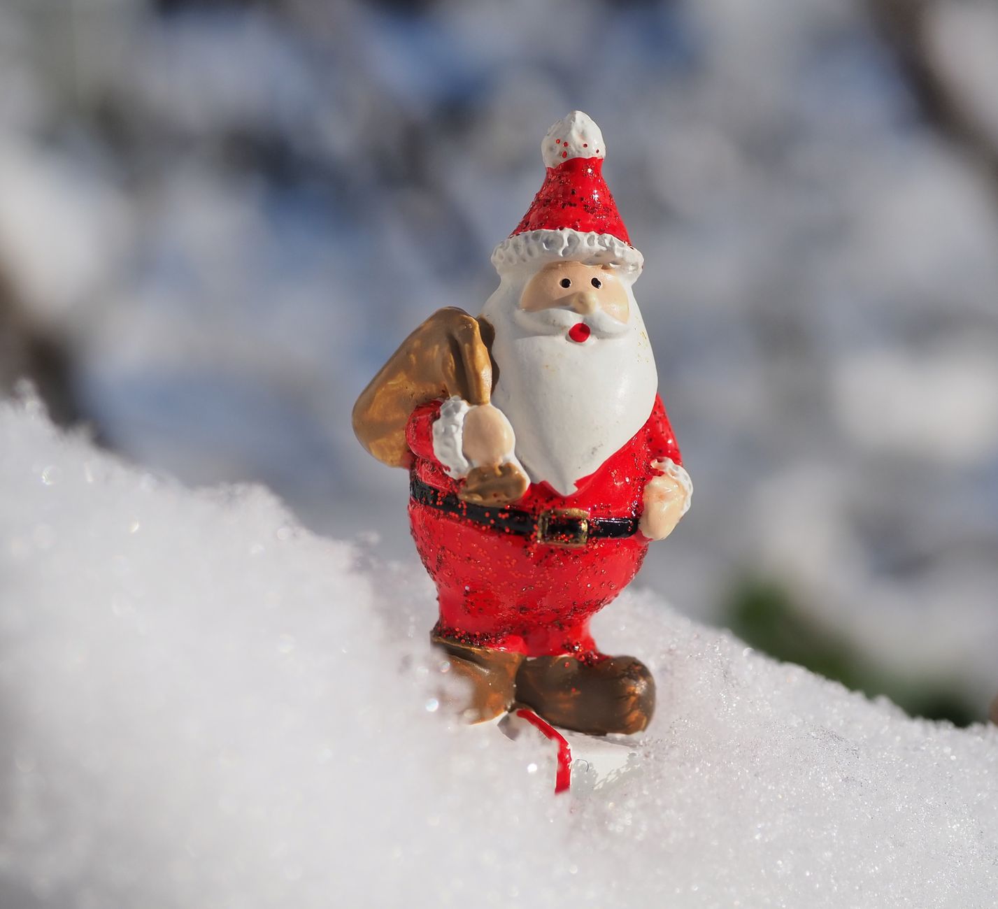 Close-up of a Santa Claus figurine on fresh winter snow, capturing the festive holiday spirit.