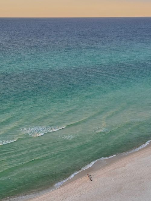 Free Aerial view of a tranquil beach with gentle waves and soft sunset hues, creating a calm atmosphere. Stock Photo