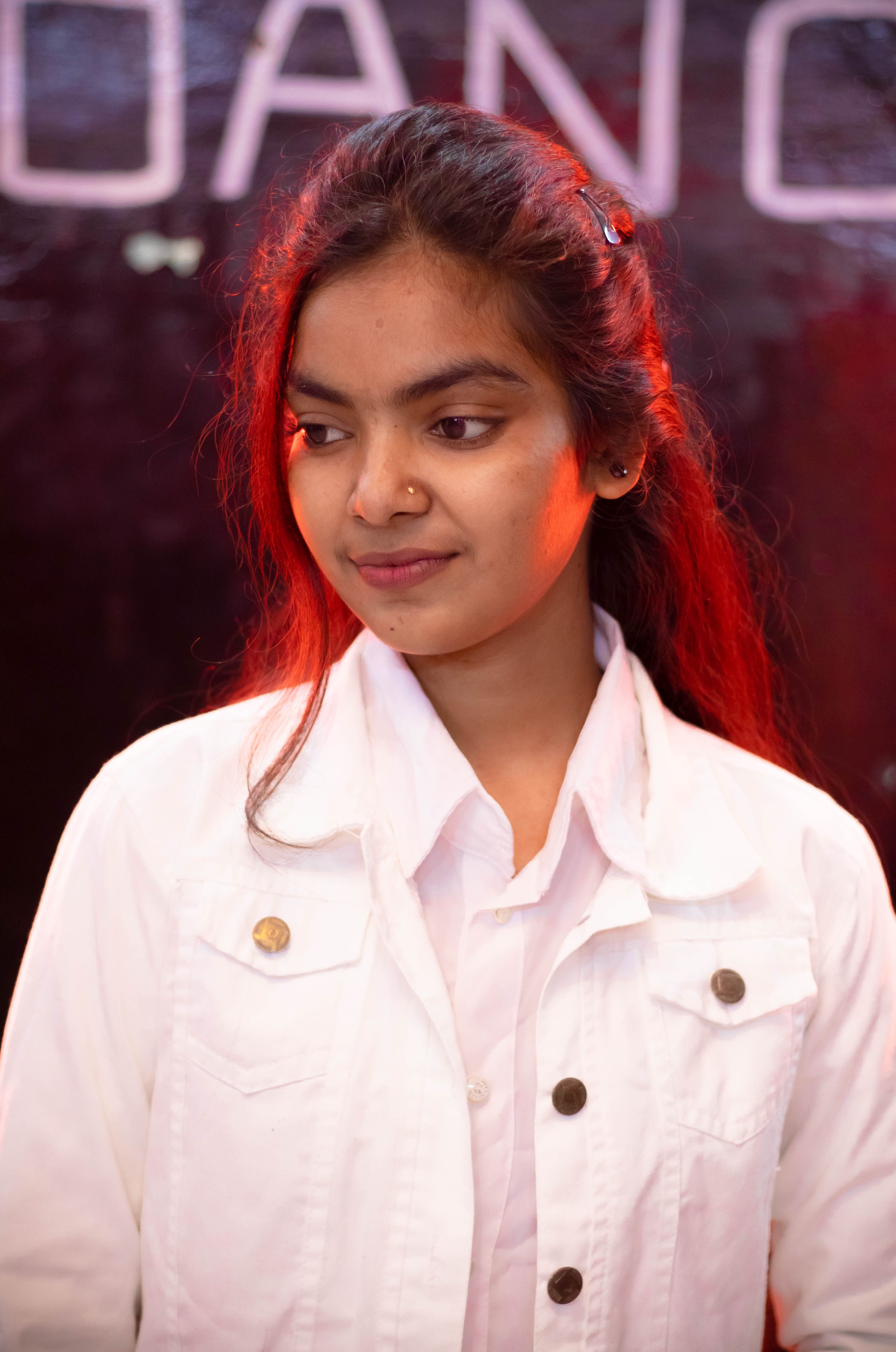 Portrait of a young woman in a white jacket with distinctive red lighting effect.