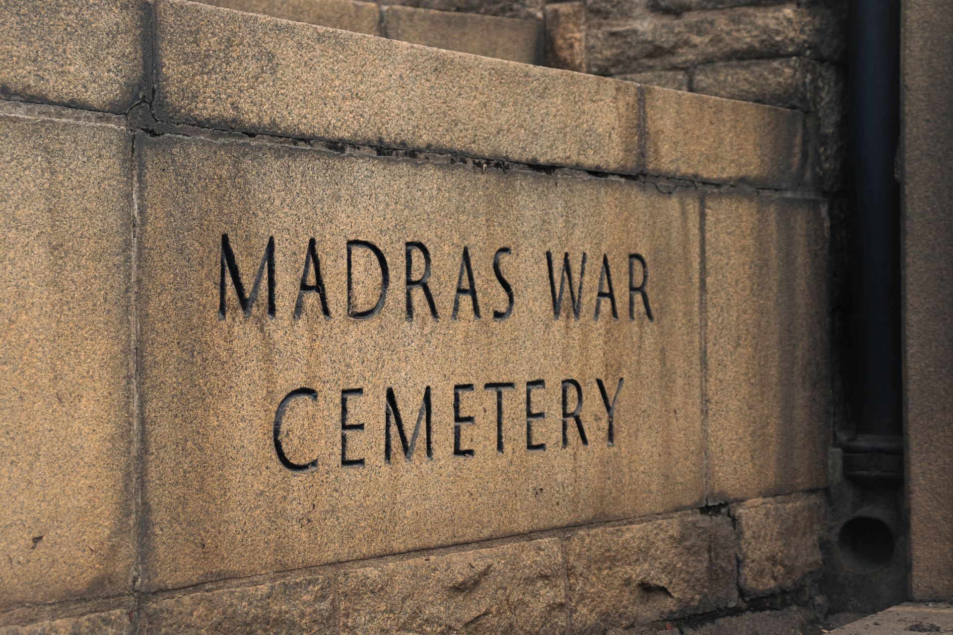 Stone wall of a war memorial with flower bouquets laid in front