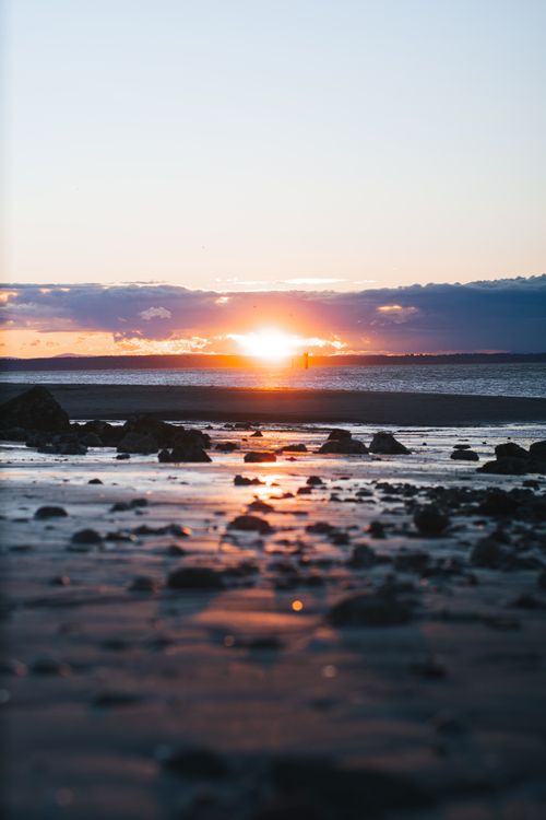 Free Majestic sunset over rocky shore, capturing serene beauty of the beach and sea. Stock Photo