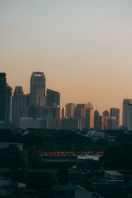 A breathtaking view of a city skyline at dusk, featuring tall skyscrapers against a soft orange sky.