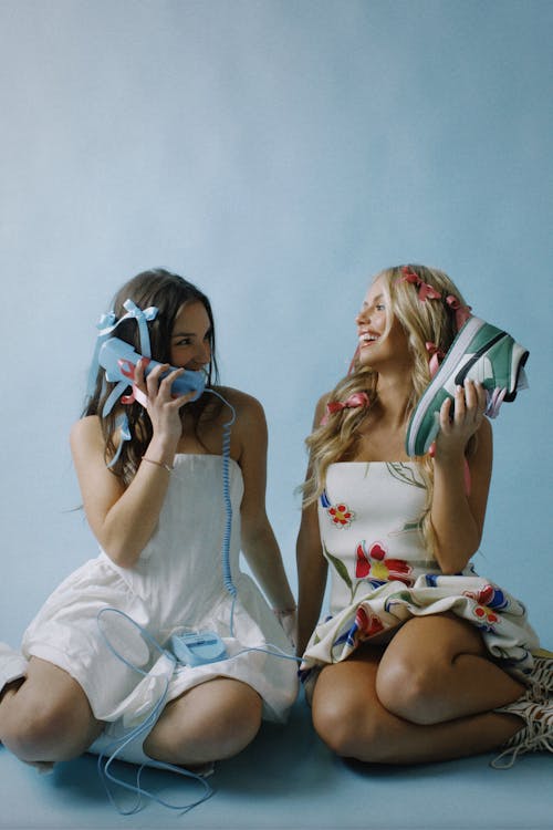 Young Girls in Dresses Sitting on the Floor and Smiling 