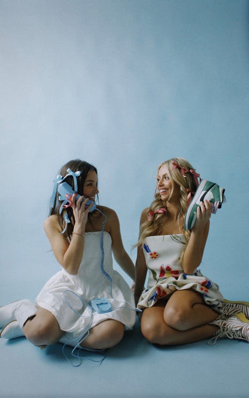 Young Girls in Dresses Sitting on the Floor and Smiling 