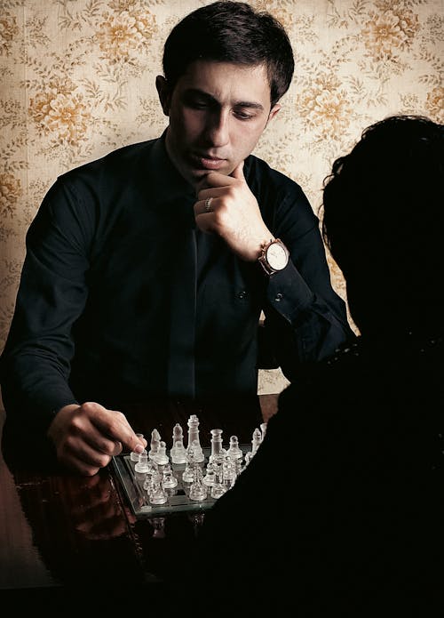 Young Man Playing Chess with Glass Pieces