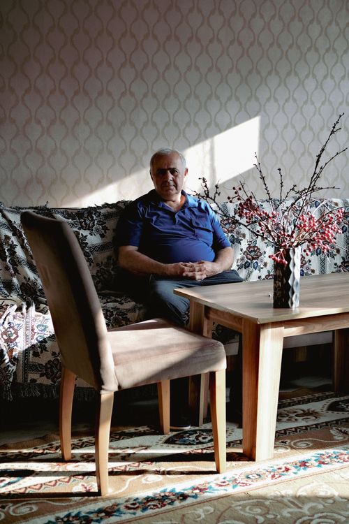 Free Senior man seated on a sofa enjoying a quiet moment with natural light. Stock Photo