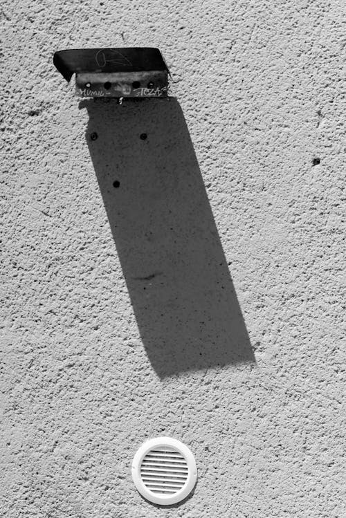 Close-up of a Lamp Attached to a Building and Casting a Shadow on the Wall 