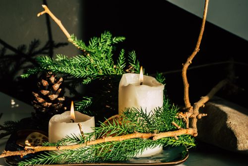Free Close-up of burning candles decorated with evergreen and pine cones, evoking a festive and cozy atmosphere. Stock Photo