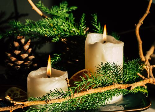 Free Warm holiday scene with candles, pine cones, and evergreen branches. Stock Photo