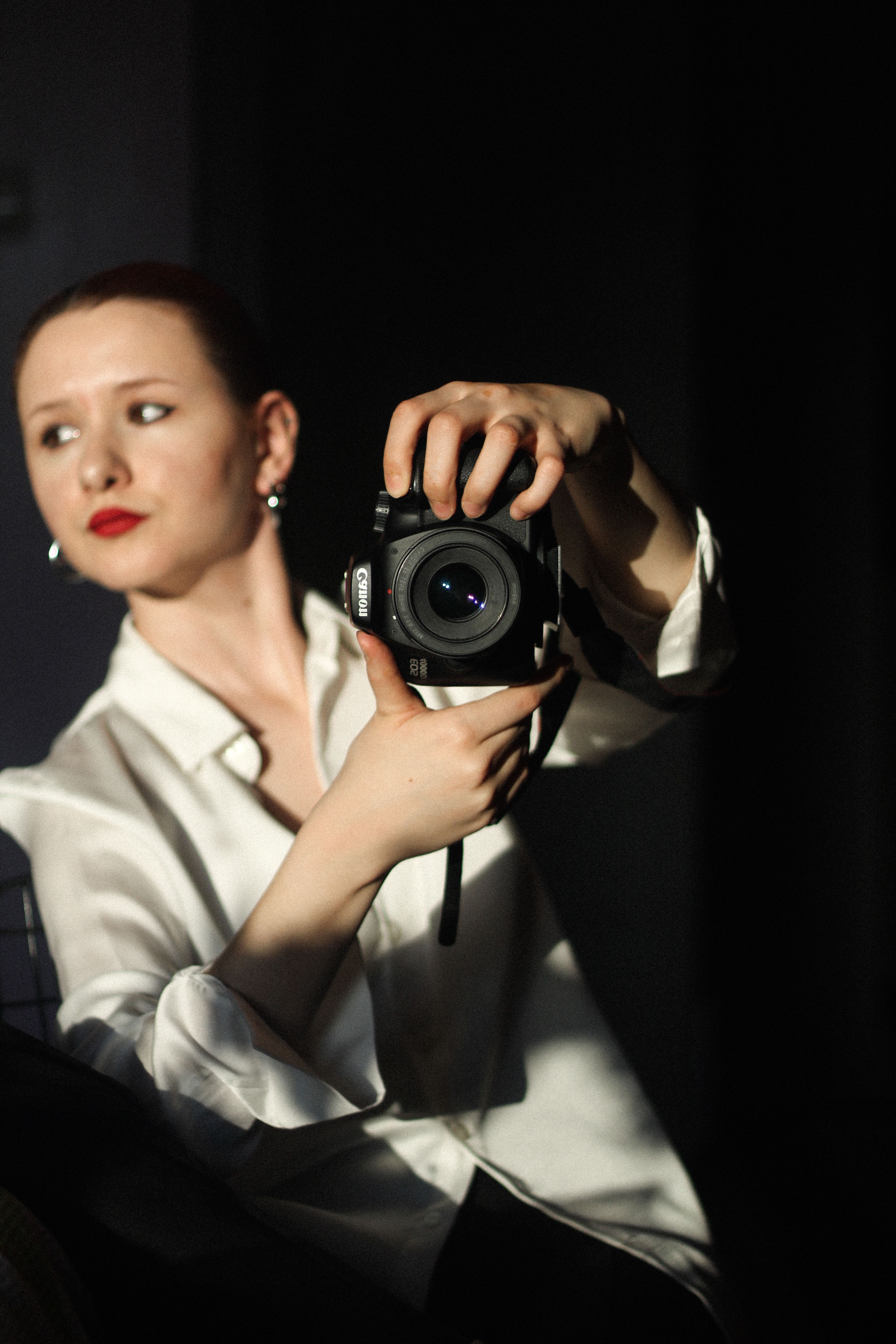 A woman captures a portrait using a DSLR camera in bright sunlight.