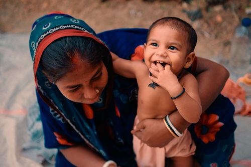 Free An intimate moment between a mother and her smiling baby, wrapped in a colorful headscarf. Stock Photo