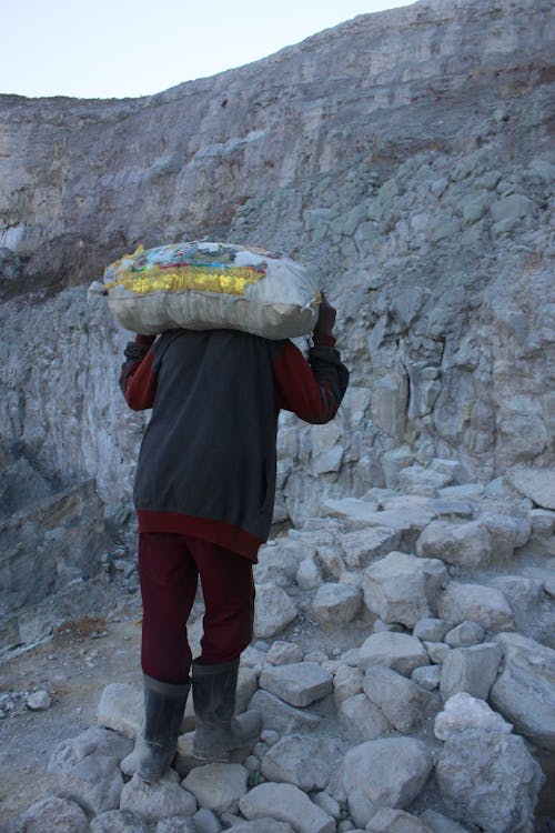 Man Walking in the Rocky Mountains and Carrying a Bag on his Shoulder 