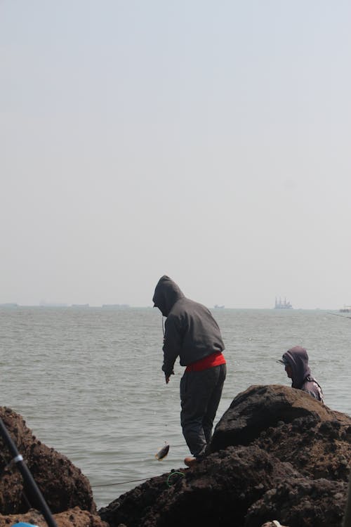 Back View of Men Fishing on the Shore 