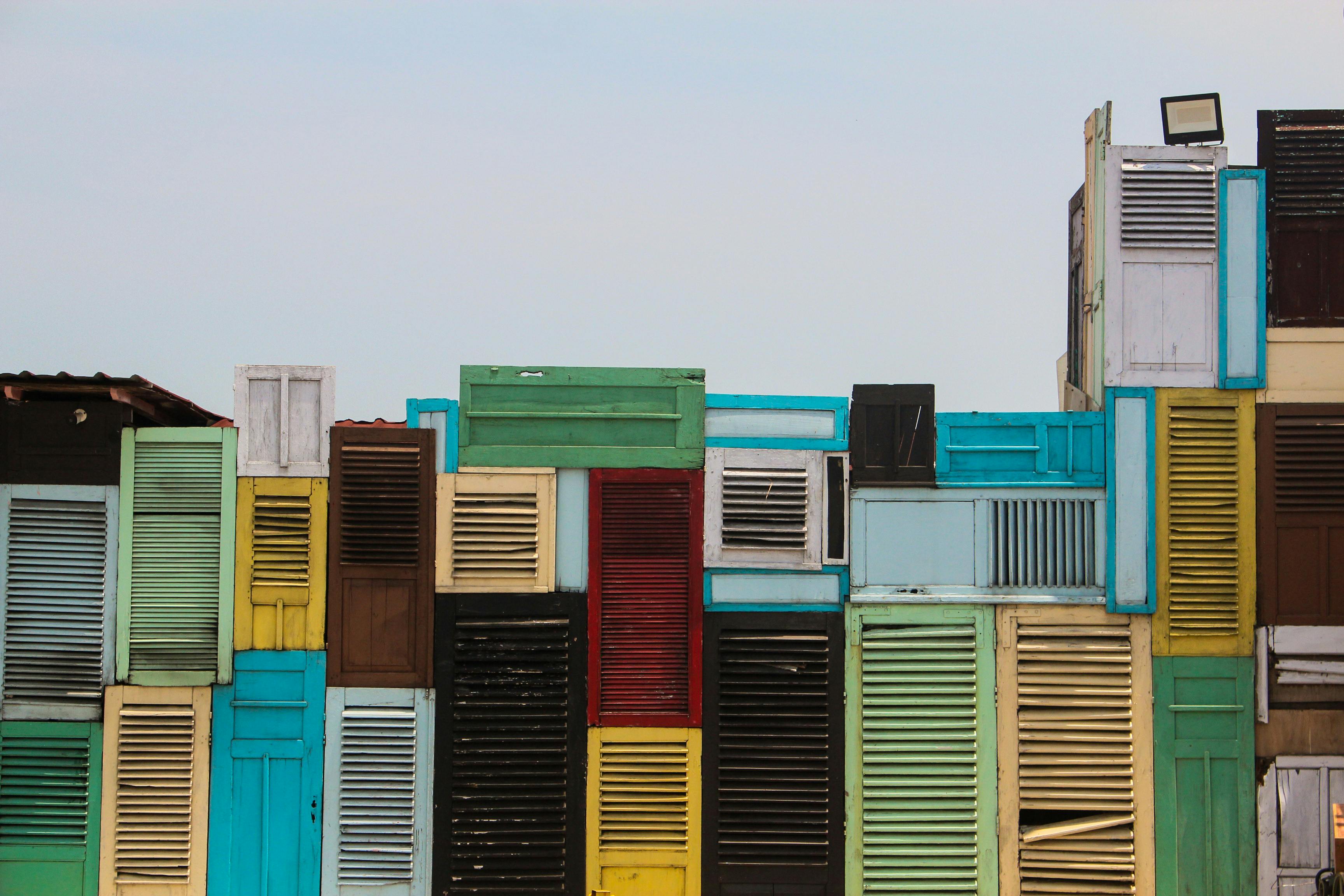 A vibrant facade made from colorful repurposed shutters showcasing creative architecture.