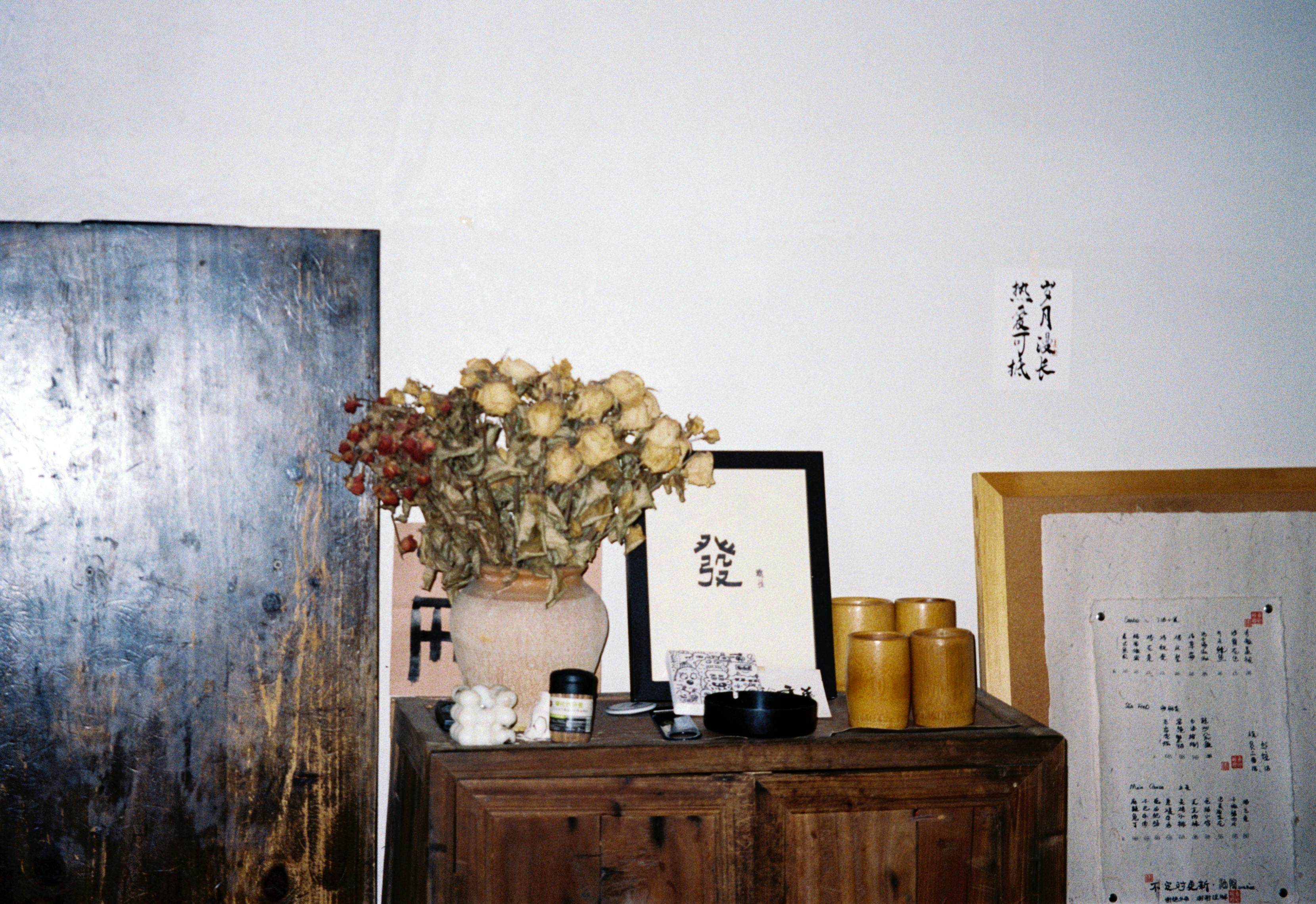 Free Rustic room interior featuring a dresser with dried bouquet and framed Asian script art. Stock Photo