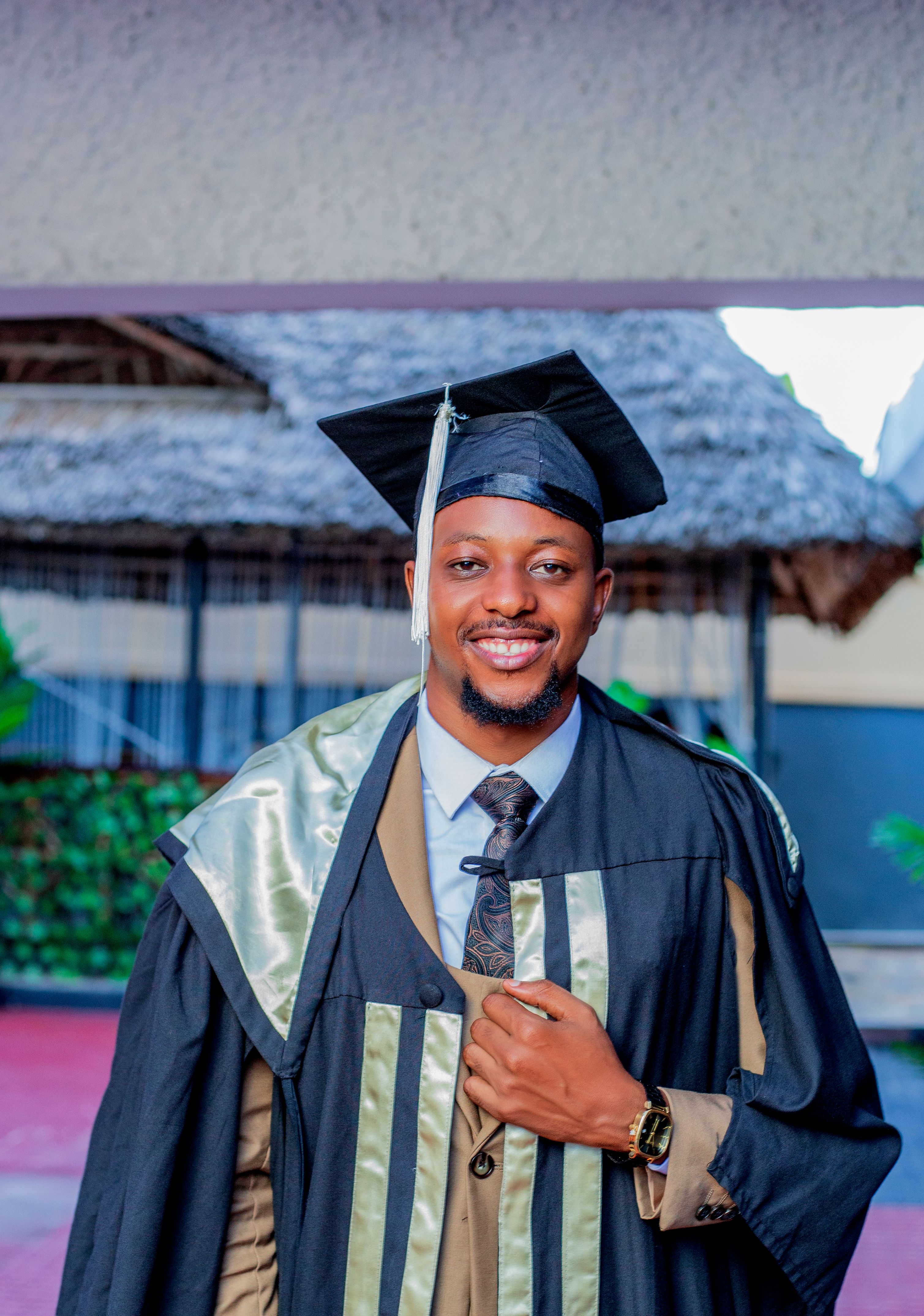 Young African man in graduation attire, celebrating with a smile.