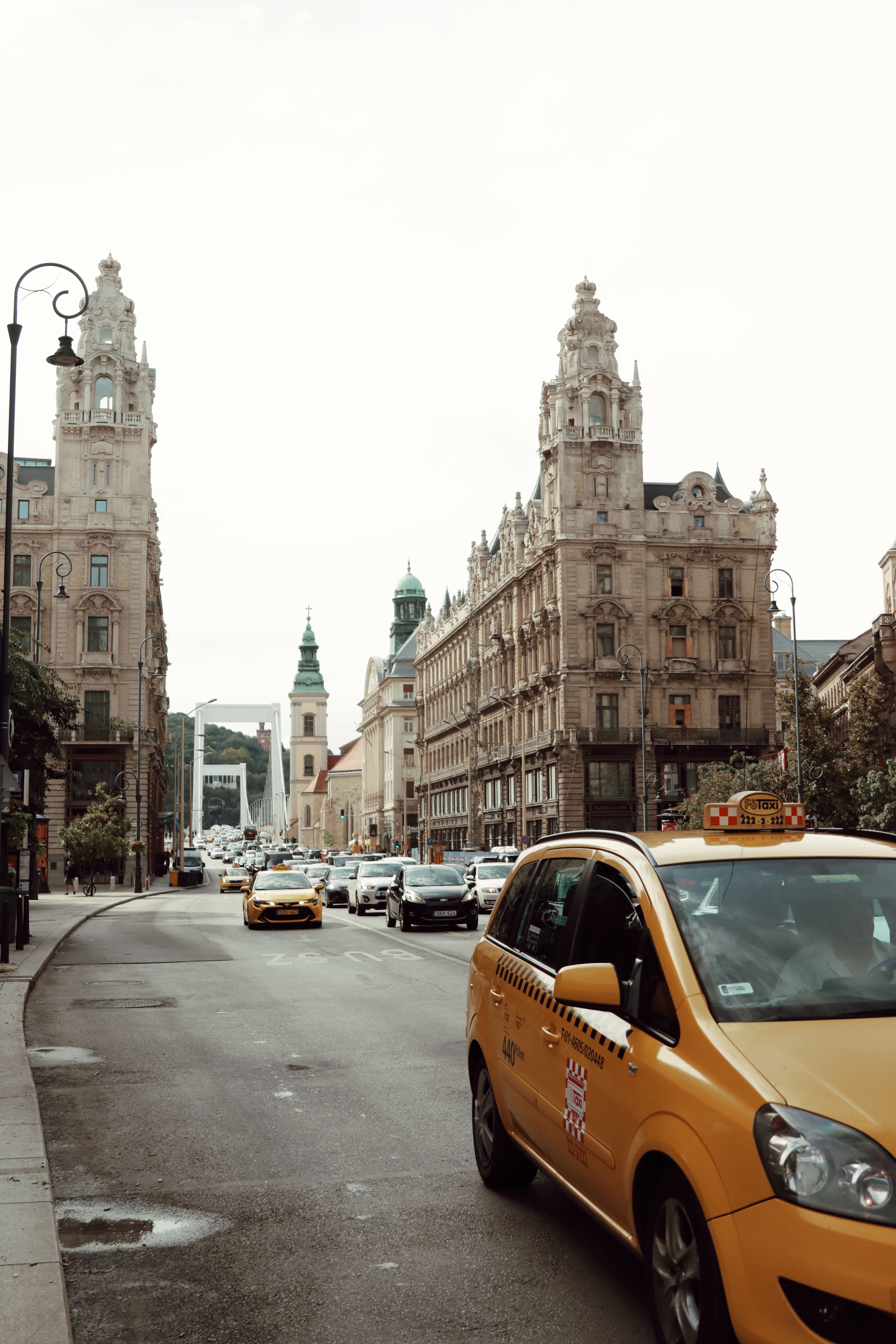 Budapest street lined with ornate classic buildings and a taxi