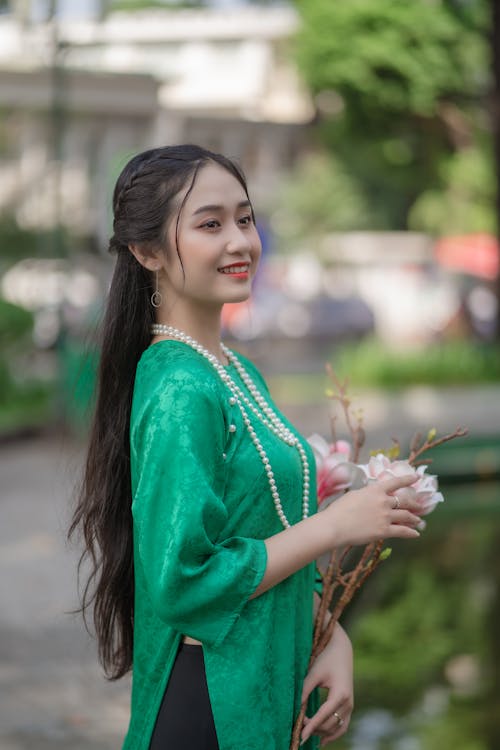 Young Woman in Traditional Clothing Standing Outside and Holding Flowers