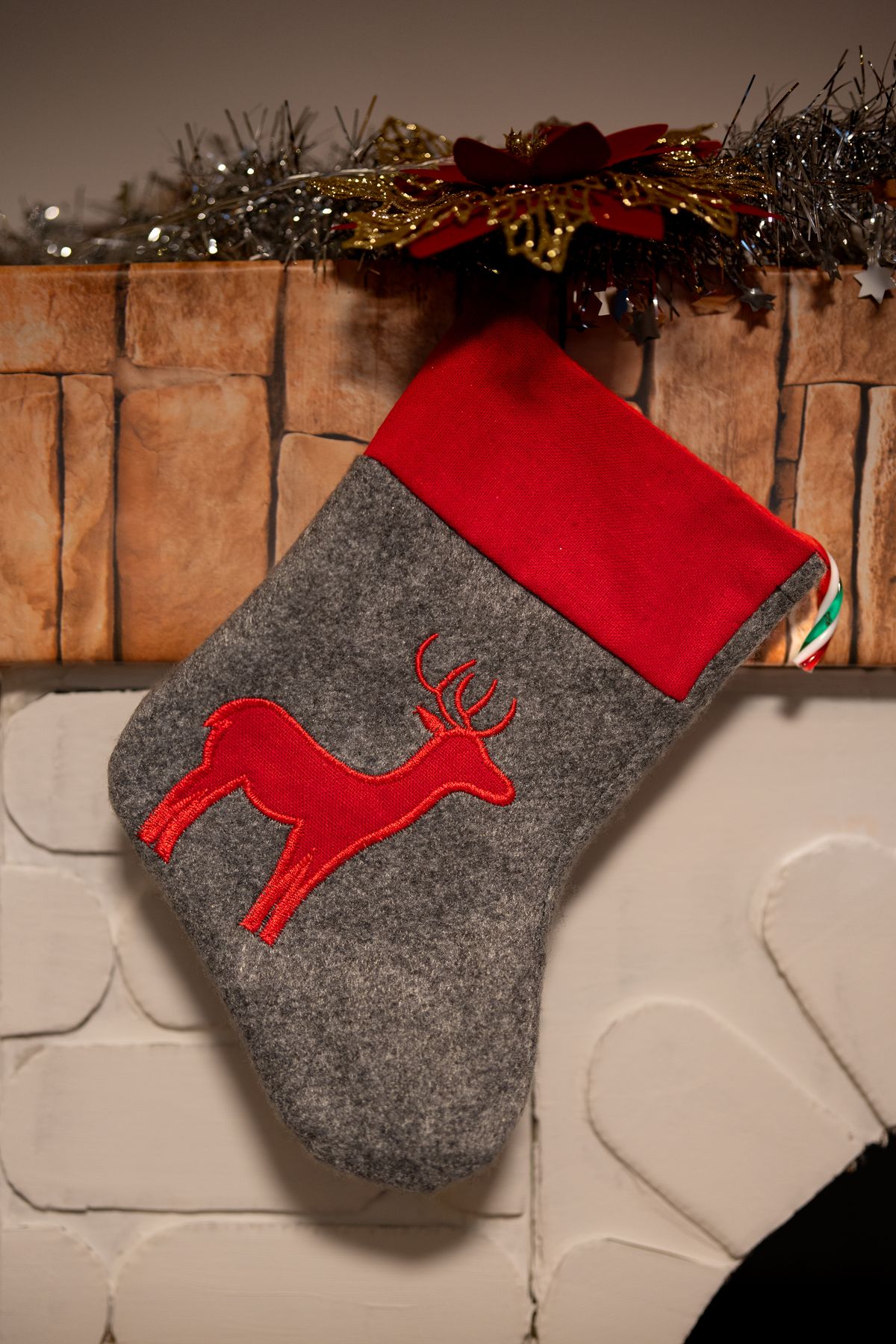 Close-up of an embroidered reindeer Christmas stocking hanging by the fireplace