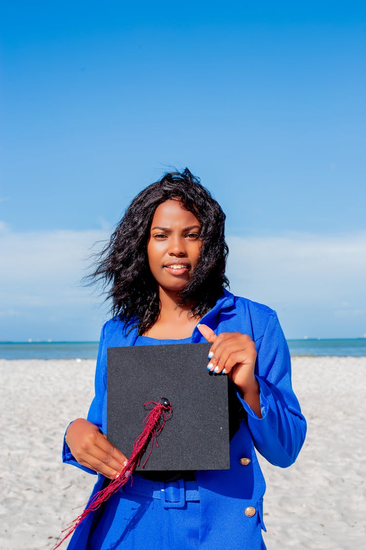 Woman In Elegant Blue Suit Holding A Black Graduation Cap