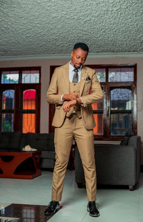 Free Elegant man in a beige suit checking his watch in a modern living room setting. Stock Photo