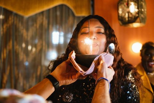 Free A joyful woman celebrating her birthday with a sparkler candle and dessert indoors in Toronto. Stock Photo